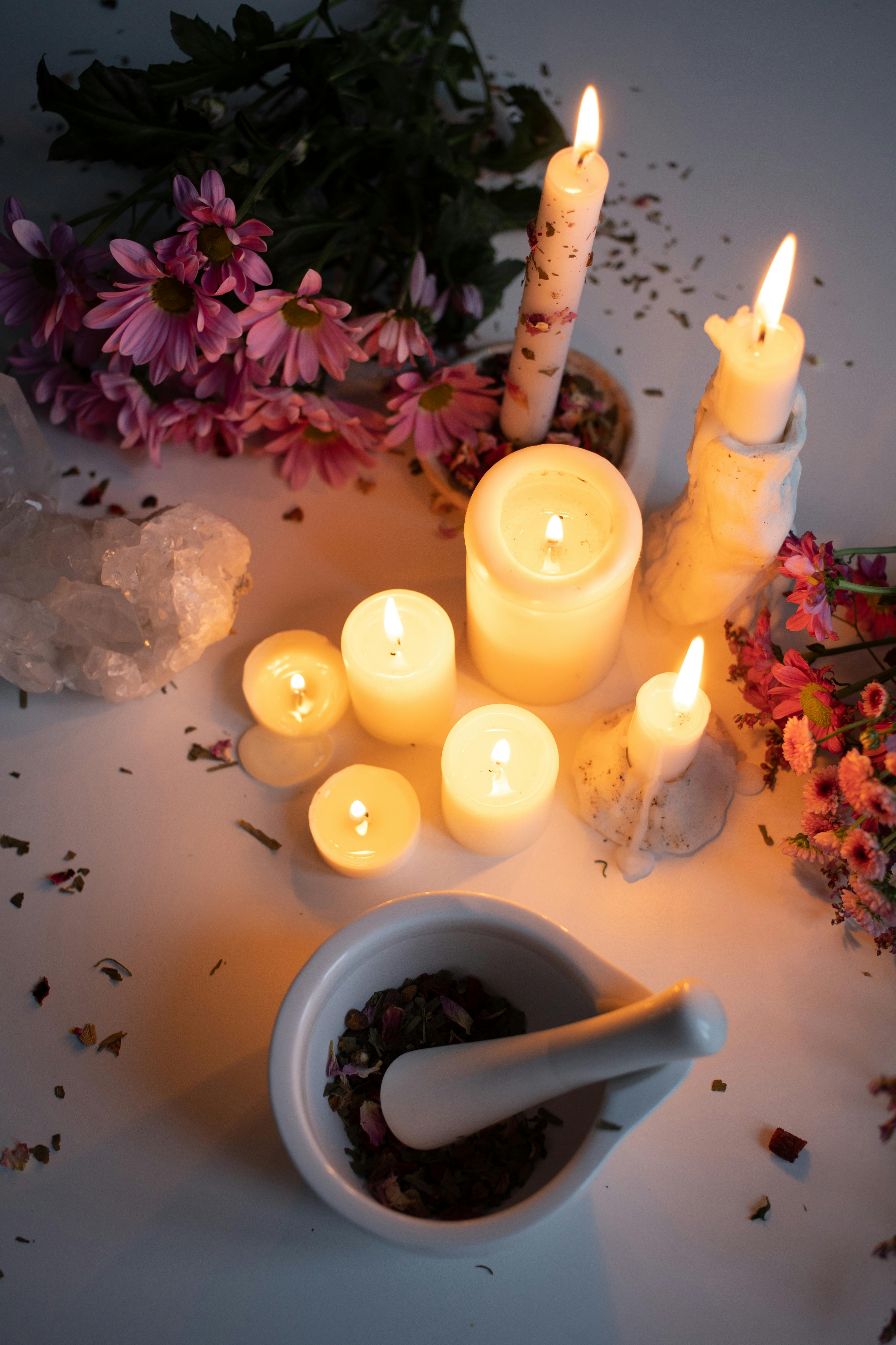  image that shows lighted candles around flowerswith pink petals arounds it pruduceing a levendar scents  