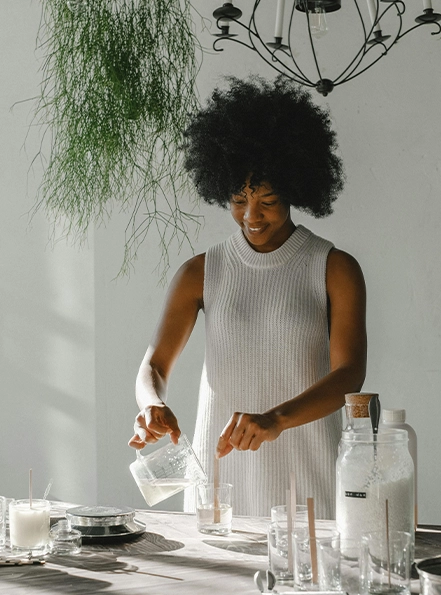 Young woman hand-pouring scented candles in Sheniqua Scented Candle studio Windsor, Ontario